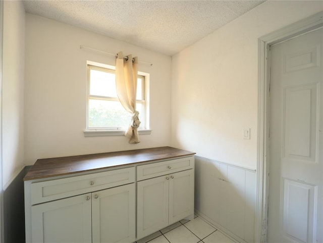 516 SW 63rd Ter, Oklahoma City, OK 73139 - kitchen with a textured ceiling, wainscoting, light tile patterned flooring, and butcher block counters