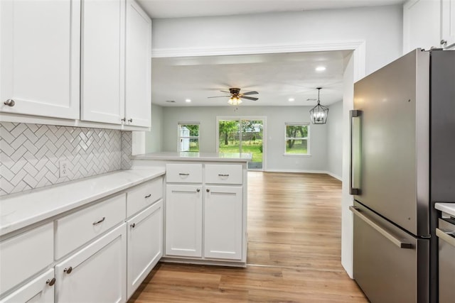 1436 NW 97th St, Oklahoma City, OK 73114 - kitchen featuring freestanding refrigerator, backsplash, white cabinetry, light wood-type flooring, and a ceiling fan