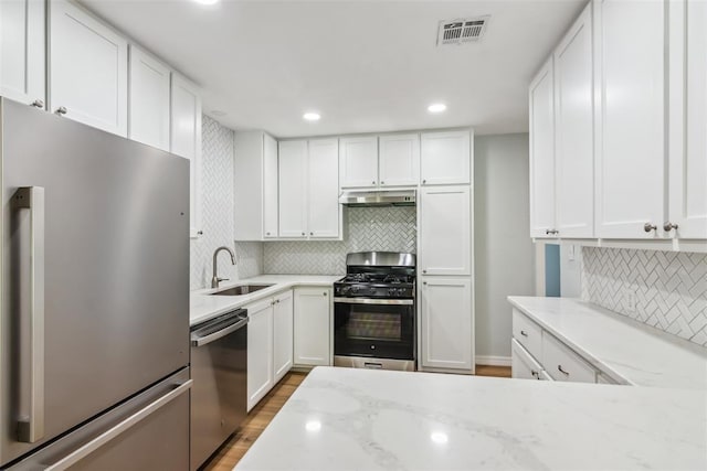 1436 NW 97th St, Oklahoma City, OK 73114 - kitchen featuring stainless steel appliances, under cabinet range hood, light stone counters, white cabinetry, and recessed lighting