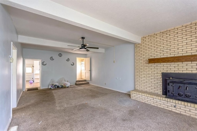 400 E Wagner Ave, Pauls Valley, OK 73075 - unfurnished living room featuring carpet floors, beamed ceiling, ceiling fan, and a wood stove