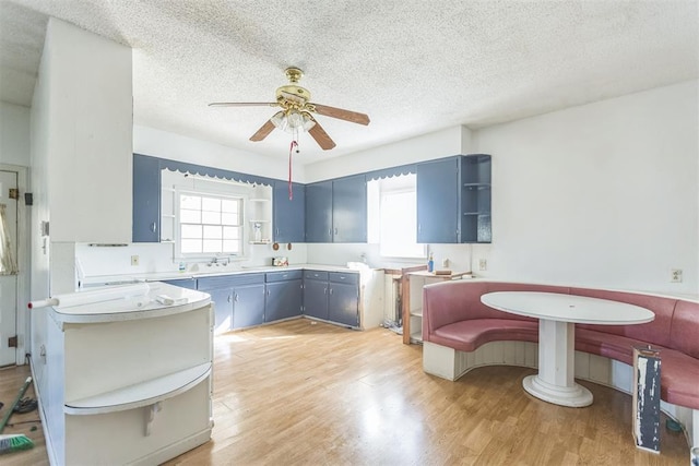 400 E Wagner Ave, Pauls Valley, OK 73075 - kitchen featuring open shelves, a ceiling fan, blue cabinetry, light wood-style floors, and a textured ceiling