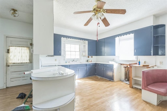 400 E Wagner Ave, Pauls Valley, OK 73075 - kitchen with open shelves, blue cabinetry, a textured ceiling, and light wood-type flooring