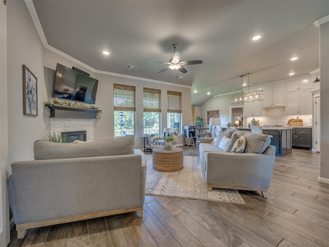 4116 Armstead Ave, Edmond, OK 73012 - living room with crown molding, ceiling fan, a stone fireplace, recessed lighting, and wood finished floors