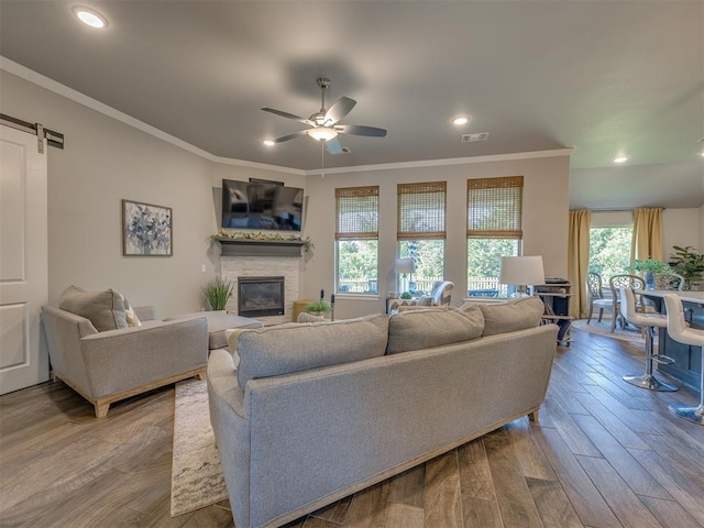 4116 Armstead Ave, Edmond, OK 73012 - living area featuring a ceiling fan, a stone fireplace, wood finished floors, crown molding, and recessed lighting