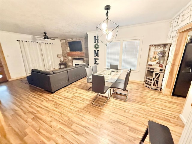 717 E Walnut St, Altus, OK 73521 - dining space featuring a stone fireplace, wood finished floors, a ceiling fan, and ornamental molding