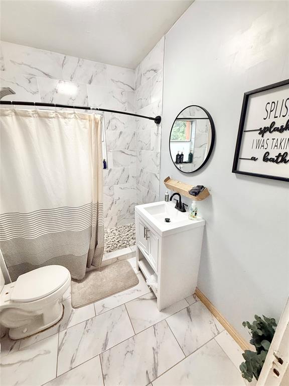 717 E Walnut St, Altus, OK 73521 - full bath featuring marble look tile flooring, curtained shower, and vanity