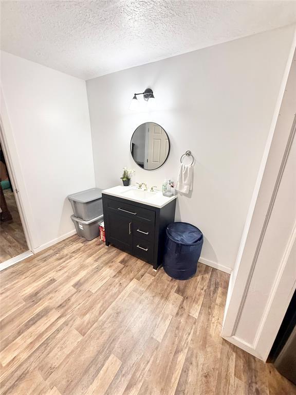 717 E Walnut St, Altus, OK 73521 - bathroom with wood finished floors, vanity, and a textured ceiling