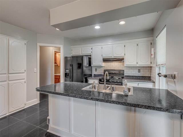 1713 SE 14th St, Moore, OK 73160 - kitchen with black refrigerator with ice dispenser, under cabinet range hood, gas stove, white cabinetry, and dark countertops