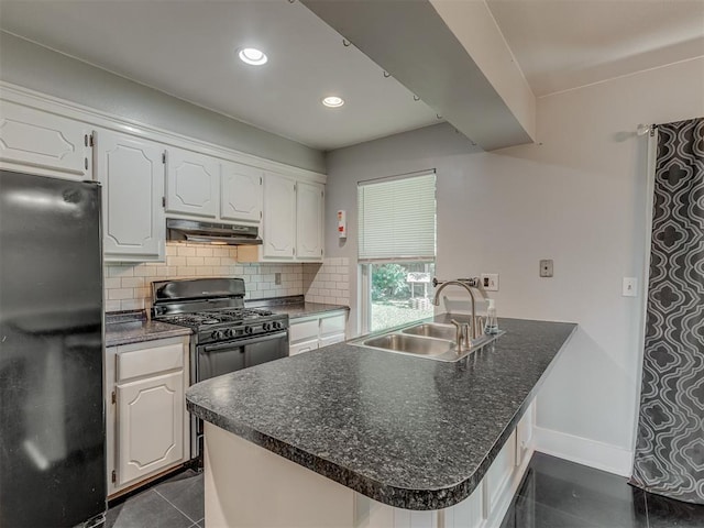 1713 SE 14th St, Moore, OK 73160 - kitchen with freestanding refrigerator, under cabinet range hood, dark countertops, backsplash, and white cabinets