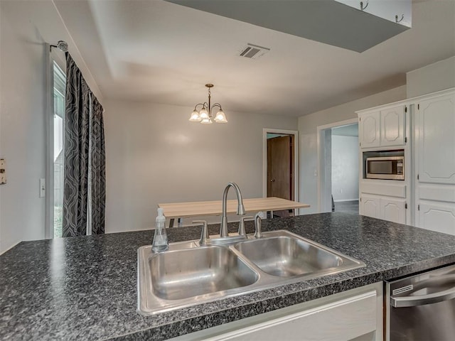 1713 SE 14th St, Moore, OK 73160 - kitchen featuring stainless steel appliances, dark countertops, a chandelier, white cabinetry, and decorative light fixtures