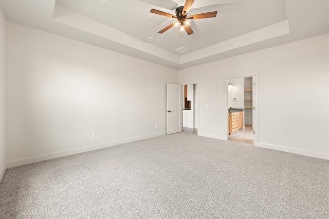 11713 NW 105th St, Yukon, OK 73099 - unfurnished bedroom featuring a tray ceiling, light carpet, ensuite bath, and a ceiling fan