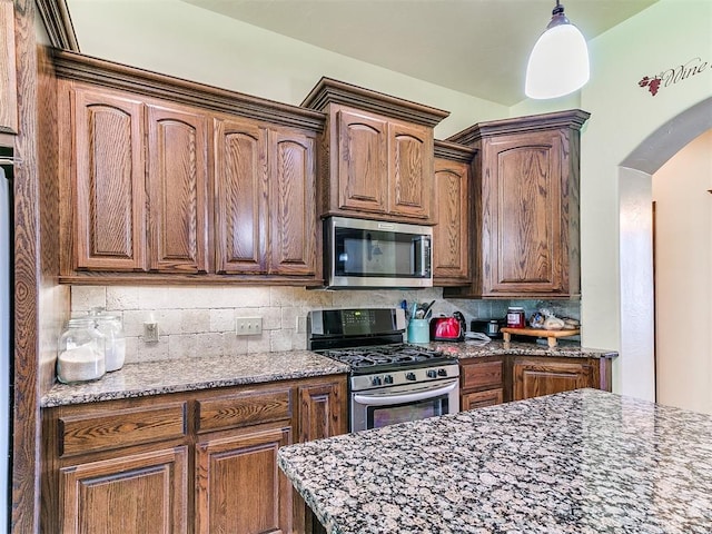 73 Sonata Ln, Shawnee, OK 74804 - kitchen featuring stainless steel appliances, arched walkways, backsplash, decorative light fixtures, and dark stone countertops