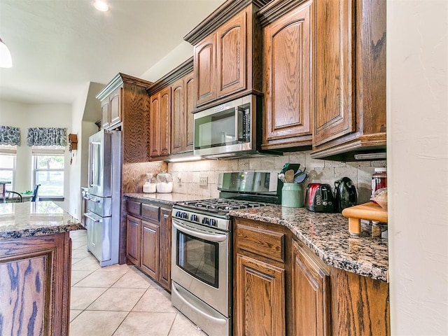 73 Sonata Ln, Shawnee, OK 74804 - kitchen with appliances with stainless steel finishes, backsplash, dark stone countertops, light tile patterned floors, and brown cabinets