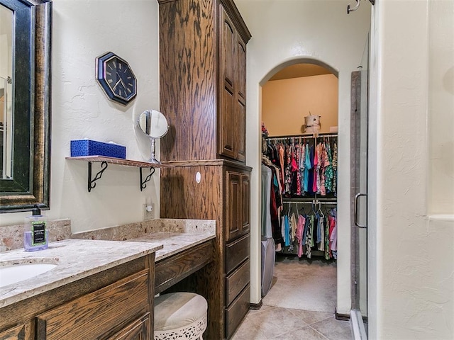 73 Sonata Ln, Shawnee, OK 74804 - bathroom with vanity, a spacious closet, a shower stall, a textured wall, and tile patterned floors