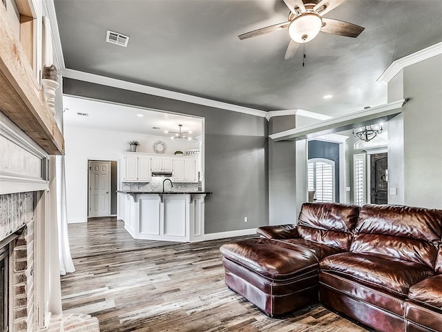 2044 Yorkshire Dr, Midwest City, OK 73130 - living area featuring a chandelier, a fireplace, wood finished floors, ceiling fan, and crown molding