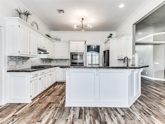 2044 Yorkshire Dr, Midwest City, OK 73130 - kitchen featuring stainless steel appliances, white cabinets, under cabinet range hood, a peninsula, and ornamental molding