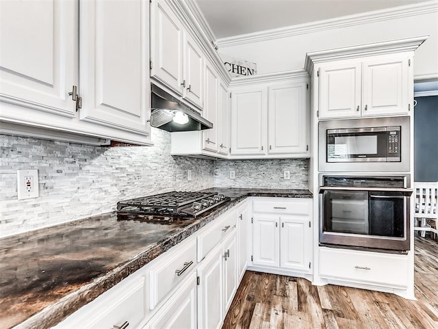 2044 Yorkshire Dr, Midwest City, OK 73130 - kitchen with stainless steel appliances, dark countertops, under cabinet range hood, white cabinets, and ornamental molding
