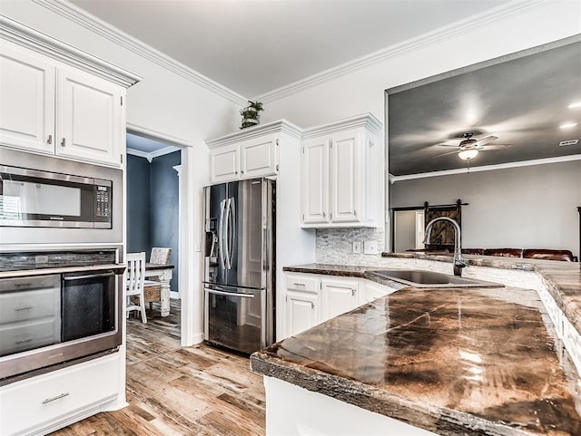 2044 Yorkshire Dr, Midwest City, OK 73130 - kitchen with stainless steel appliances, light wood-style floors, crown molding, dark countertops, and white cabinets