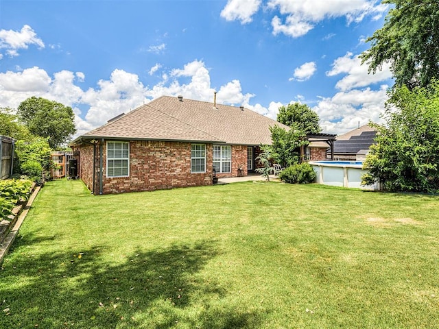 2044 Yorkshire Dr, Midwest City, OK 73130 - rear view of property featuring a fenced backyard, brick siding, roof with shingles, an outdoor pool, and a patio area