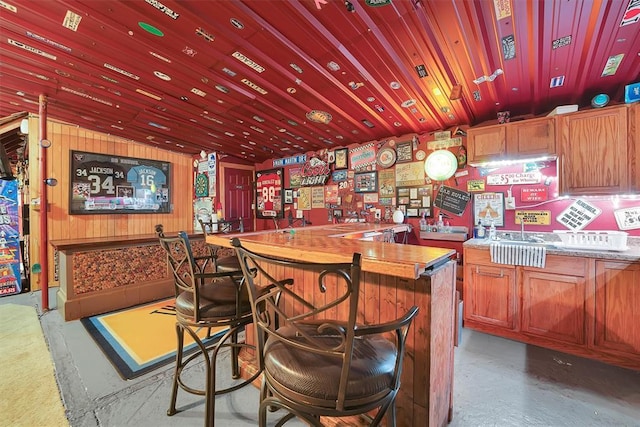 22117 E 1250th Rd, Rocky, OK 73661 - indoor dry bar featuring concrete flooring, vaulted ceiling, and wood walls
