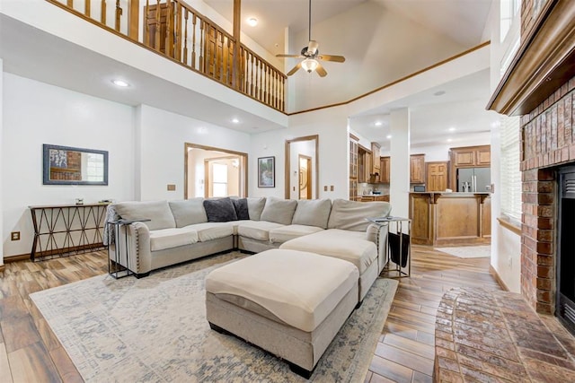 11409 SW 109th St, Mustang, OK 73064 - living room with a fireplace, light wood-style flooring, ceiling fan, a high ceiling, and plenty of natural light