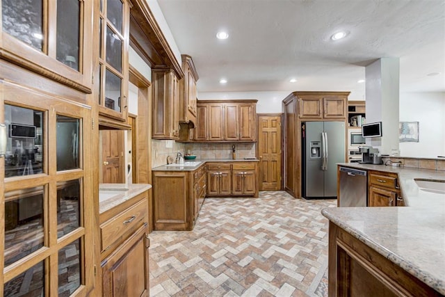 11409 SW 109th St, Mustang, OK 73064 - kitchen with stainless steel appliances, brown cabinets, backsplash, recessed lighting, and light stone counters