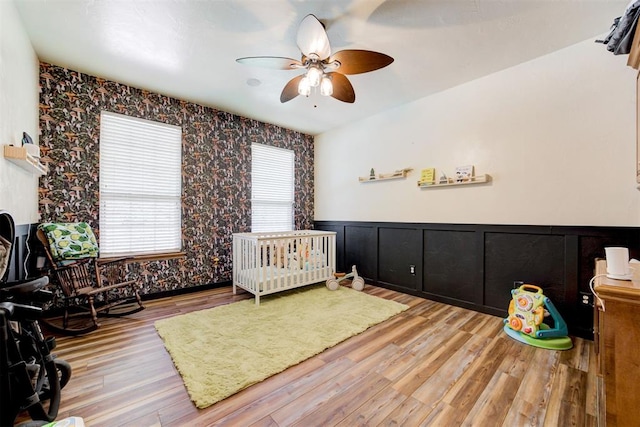 11409 SW 109th St, Mustang, OK 73064 - bedroom featuring a wainscoted wall, wallpapered walls, light wood-style floors, and a ceiling fan