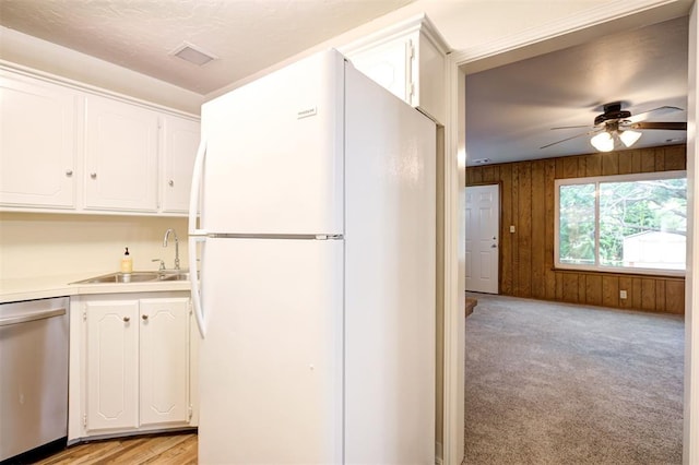 521 NW 50th St, Oklahoma City, OK 73118 - kitchen with freestanding refrigerator, stainless steel dishwasher, a ceiling fan, wood walls, and white cabinets