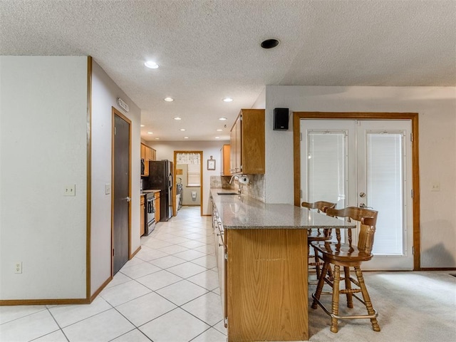 700 S Willowood Dr, Yukon, OK 73099 - kitchen featuring french doors, a breakfast bar, stainless steel electric range, freestanding refrigerator, and a peninsula