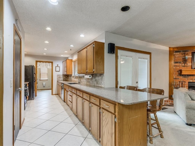 700 S Willowood Dr, Yukon, OK 73099 - kitchen featuring a peninsula, a breakfast bar area, a textured ceiling, stainless steel dishwasher, and recessed lighting