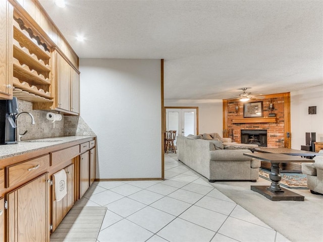 700 S Willowood Dr, Yukon, OK 73099 - kitchen featuring open shelves, tasteful backsplash, ceiling fan, a textured ceiling, and a fireplace
