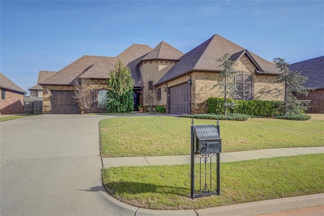 9020 NW 147th Ter, Yukon, OK 73099 - french country inspired facade featuring an attached garage, concrete driveway, a front lawn, and stone siding