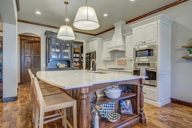 9020 NW 147th Ter, Yukon, OK 73099 - kitchen with stainless steel appliances, custom range hood, arched walkways, crown molding, and dark wood-type flooring