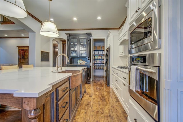 9020 NW 147th Ter, Yukon, OK 73099 - kitchen featuring appliances with stainless steel finishes, arched walkways, crown molding, wood finished floors, and white cabinets