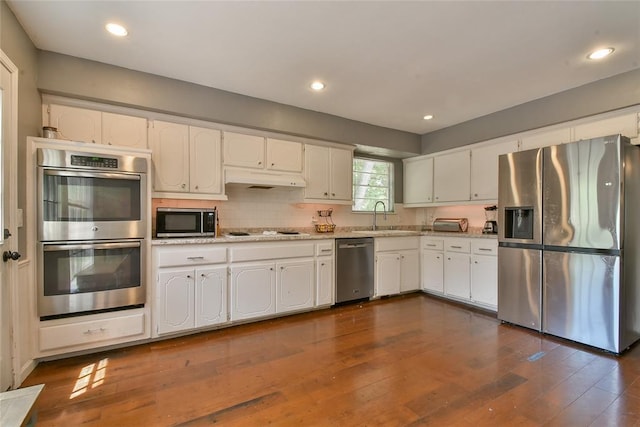 8800 Stoneleigh Ct, Oklahoma City, OK 73132 - kitchen with stainless steel appliances, under cabinet range hood, white cabinets, dark wood-type flooring, and recessed lighting