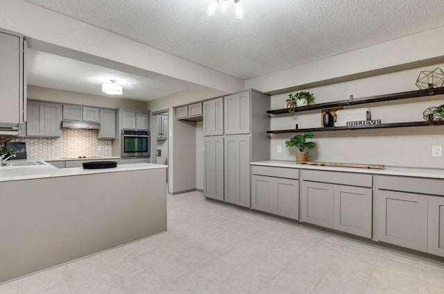 1536 Kingsgate Rd, Oklahoma City, OK 73159 - kitchen featuring gray cabinetry, stainless steel oven, open shelves, a textured ceiling, and tasteful backsplash