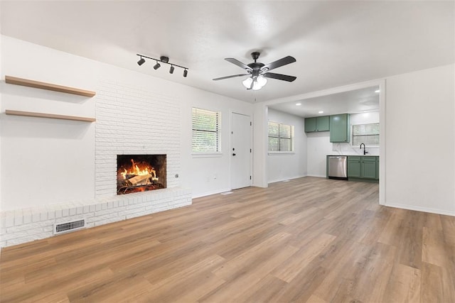 9617 Georgia Ave, Oklahoma City, OK 73120 - unfurnished living room with ceiling fan, a brick fireplace, and light wood-style flooring