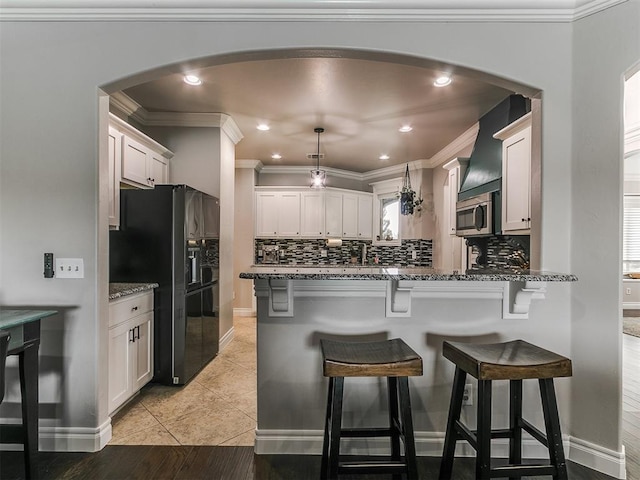 7032 NW 159th Pl, Edmond, OK 73013 - kitchen featuring black refrigerator with ice dispenser, arched walkways, a peninsula, decorative backsplash, and crown molding