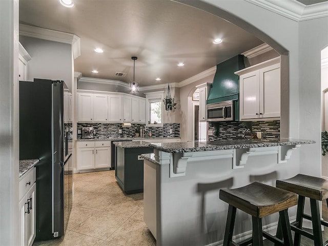 7032 NW 159th Pl, Edmond, OK 73013 - kitchen with black fridge, arched walkways, a peninsula, stainless steel microwave, and decorative backsplash