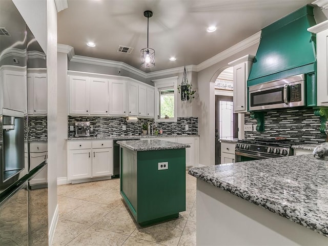 7032 NW 159th Pl, Edmond, OK 73013 - kitchen with appliances with stainless steel finishes, backsplash, range hood, crown molding, and arched walkways