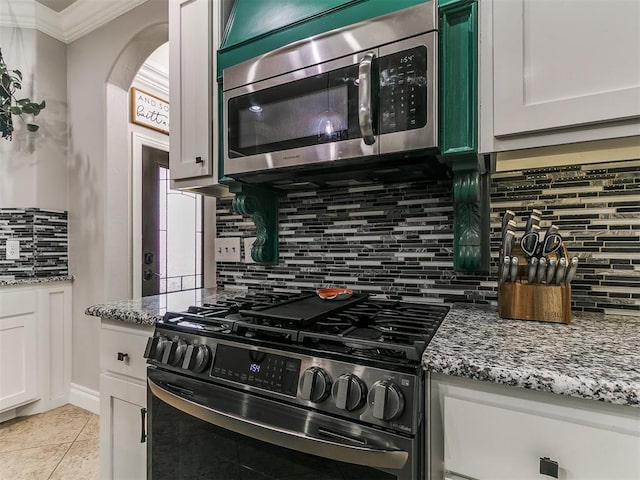 7032 NW 159th Pl, Edmond, OK 73013 - kitchen with appliances with stainless steel finishes, backsplash, light stone counters, ornamental molding, and light tile patterned floors