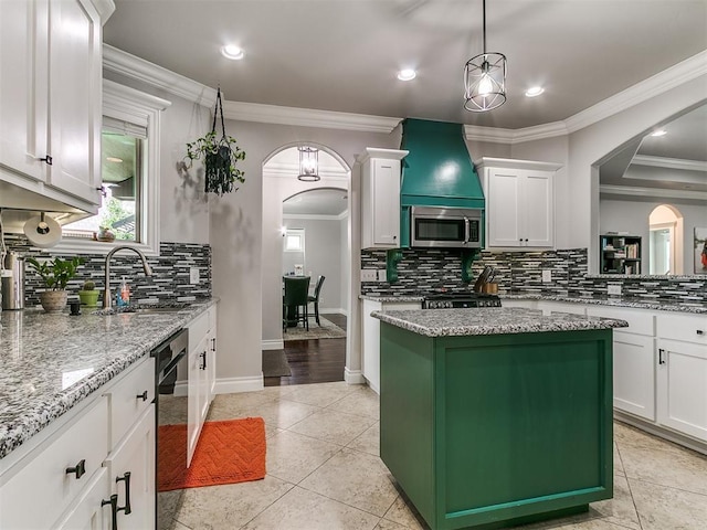 7032 NW 159th Pl, Edmond, OK 73013 - kitchen with stainless steel microwave, arched walkways, backsplash, crown molding, and white cabinets