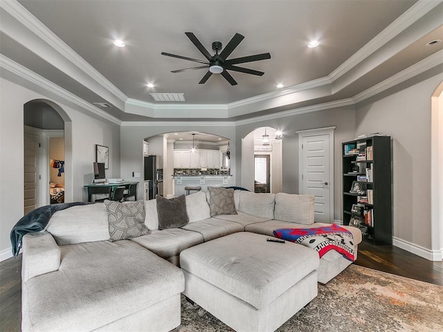 7032 NW 159th Pl, Edmond, OK 73013 - living area featuring ceiling fan, a raised ceiling, dark wood-type flooring, arched walkways, and crown molding