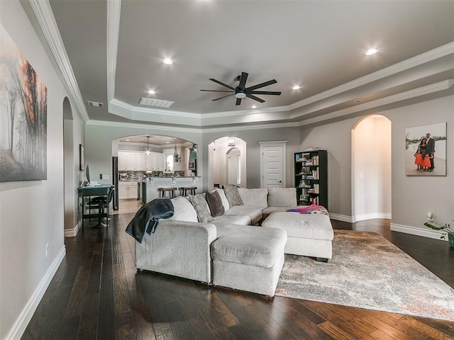 7032 NW 159th Pl, Edmond, OK 73013 - living room with arched walkways, ceiling fan, a raised ceiling, dark wood finished floors, and ornamental molding