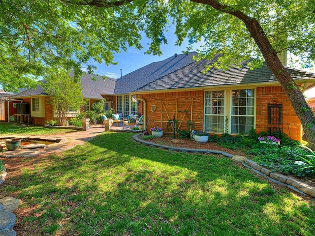 117 S Lexington Way, Edmond, OK 73012 - back of house featuring brick siding, a lawn, a patio, and roof with shingles