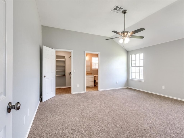 4917 SE 89th Ter, Oklahoma City, OK 73135 - unfurnished bedroom with carpet flooring, vaulted ceiling, a walk in closet, multiple windows, and ceiling fan