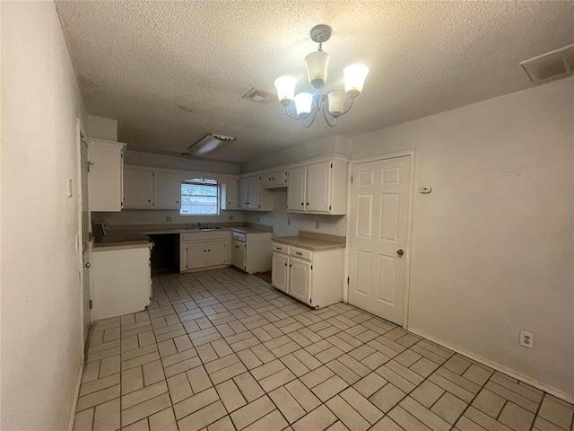 5333 Coble St, Oklahoma City, OK 73135 - kitchen featuring brick patterned floors, a textured ceiling, white cabinetry, and a chandelier
