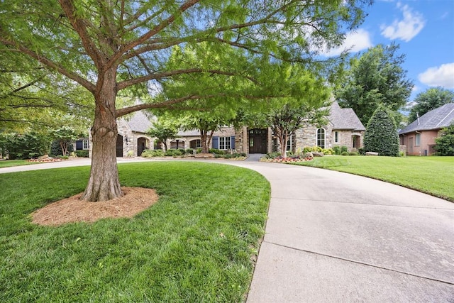 1608 Mulholland Dr, Edmond, OK 73003 - view of front of home with stone siding, a front yard, and curved driveway