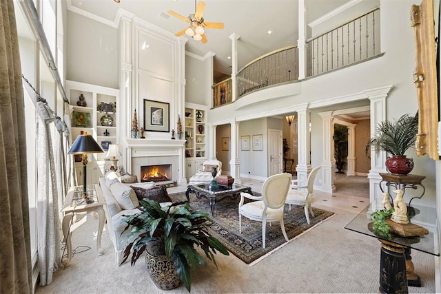 1608 Mulholland Dr, Edmond, OK 73003 - living area with ornate columns, a towering ceiling, a fireplace, built in features, and a ceiling fan