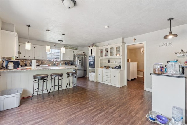 11900 Surrey Ln, Yukon, OK 73099 - kitchen with stainless steel fridge, black oven, a peninsula, a warming drawer, and dark wood-type flooring